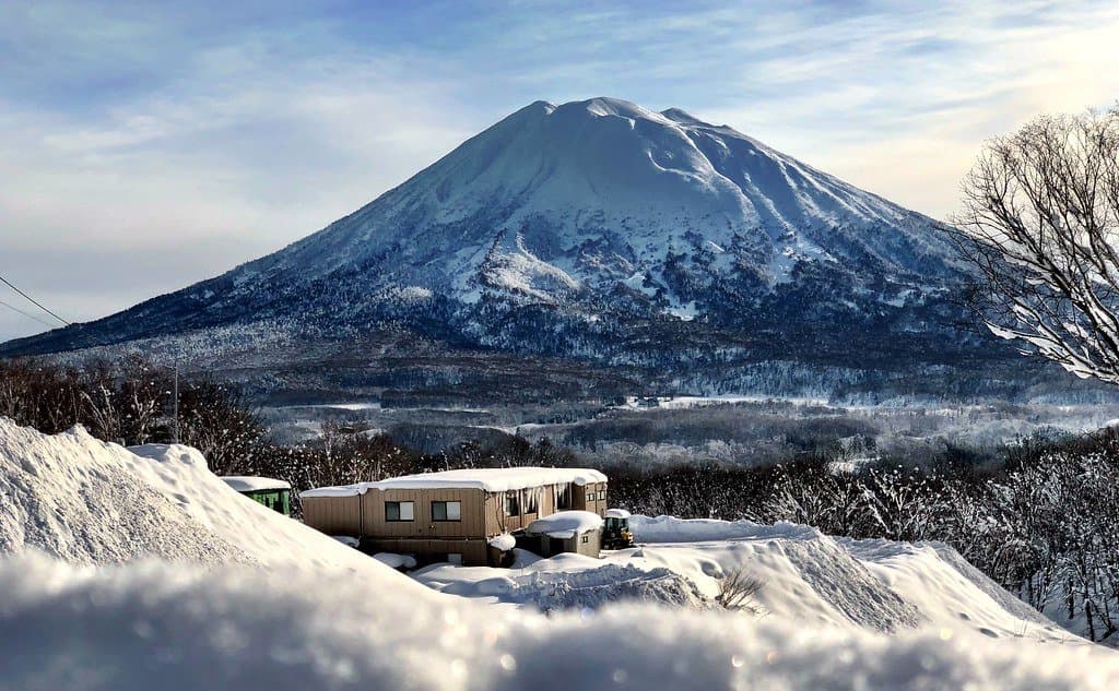 A snow-covered house with Mount Yotei behind it in winter